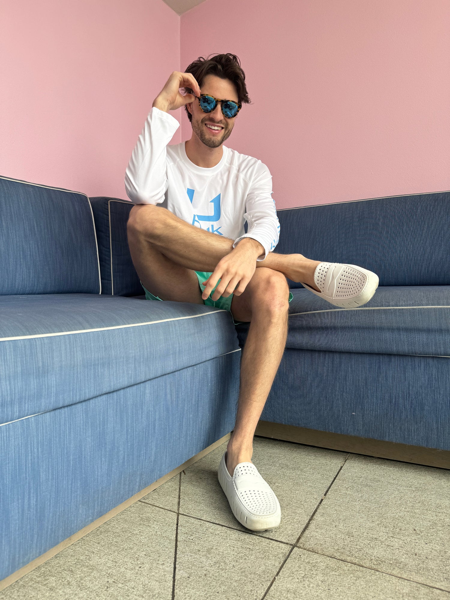 Man sitting on a blue bench with a pink wall background