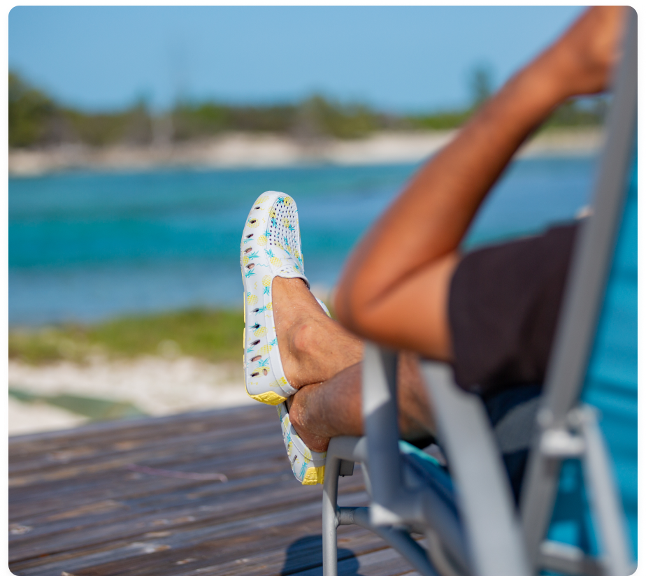 Man sitting in folding chair on a dock wearing floafers