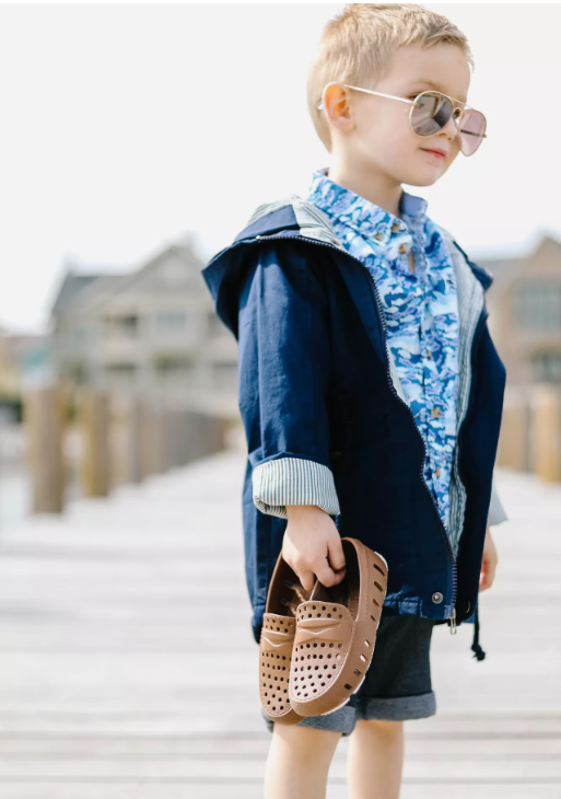 Child holding brown floafers on dock